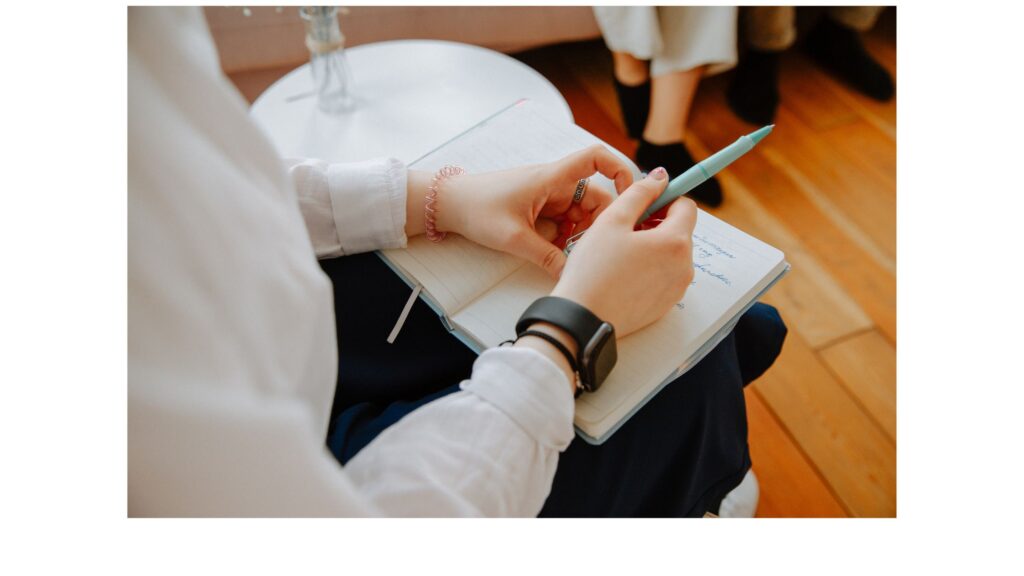 hands holding a pen over a blank notebook